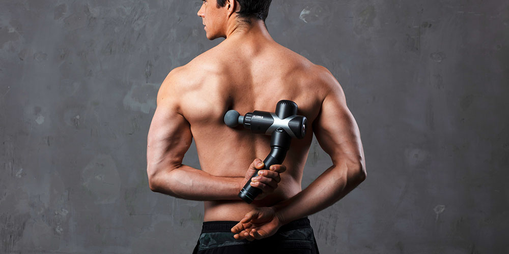 A man massaging his back with a massage gun.